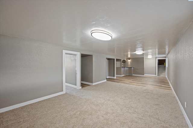 finished below grade area with carpet flooring, a textured wall, and baseboards