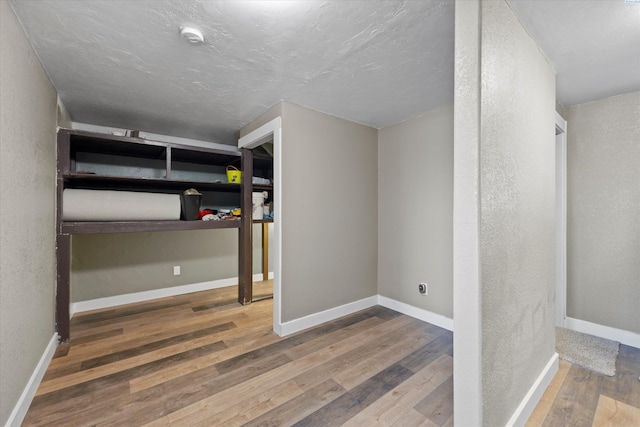 unfurnished bedroom with baseboards, wood-type flooring, and a textured wall