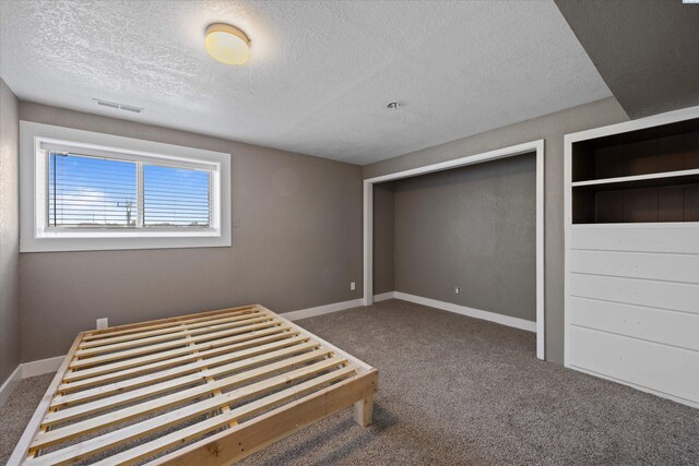 unfurnished bedroom featuring visible vents, baseboards, a textured ceiling, and carpet flooring