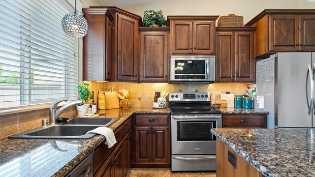 1905 S Harrison St, Kennewick, WA 99338 - kitchen with stainless steel appliances, a sink, backsplash, dark stone counters, and hanging light fixtures