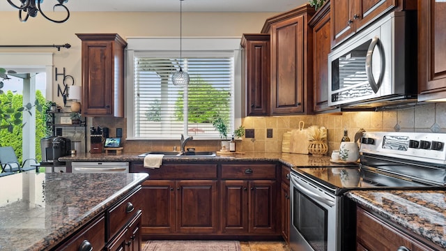 1905 S Harrison St, Kennewick, WA 99338 - kitchen with appliances with stainless steel finishes, a sink, backsplash, dark stone counters, and pendant lighting