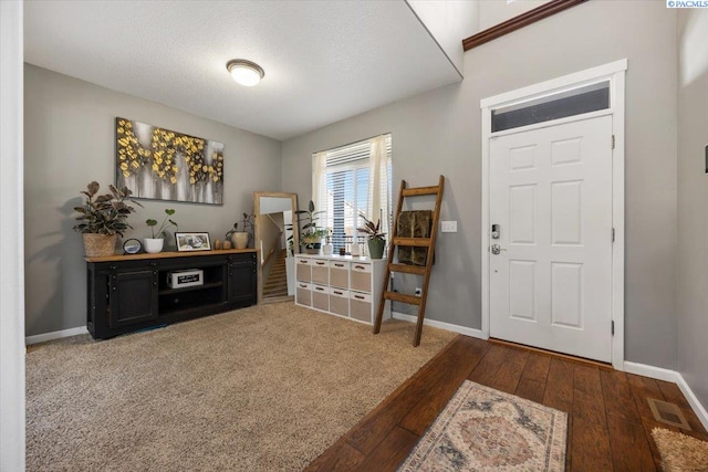 foyer entrance featuring wood-type flooring, visible vents, and baseboards