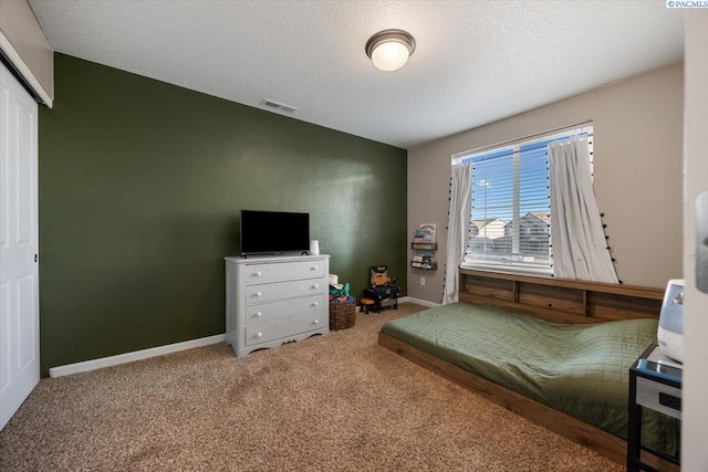 unfurnished bedroom with visible vents, baseboards, carpet, a textured ceiling, and a closet