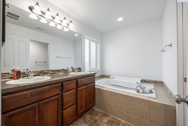 full bathroom featuring visible vents, a sink, a garden tub, and double vanity