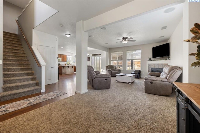 living room featuring a wealth of natural light, a fireplace, stairway, and carpet