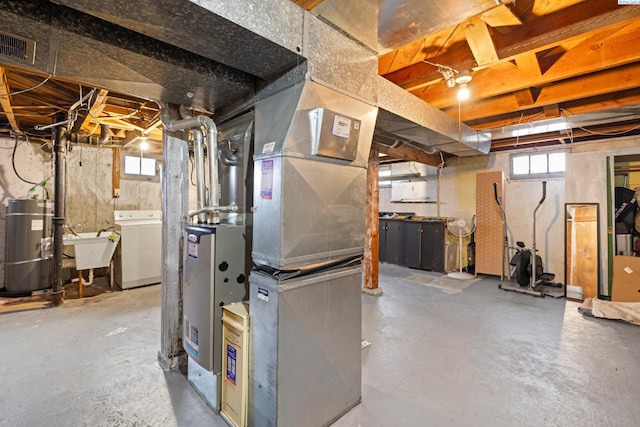 basement with water heater, washer / clothes dryer, a sink, and visible vents