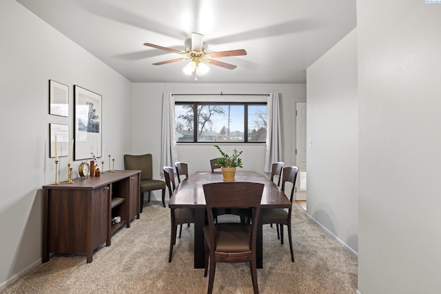 dining area with baseboards, ceiling fan, and light colored carpet