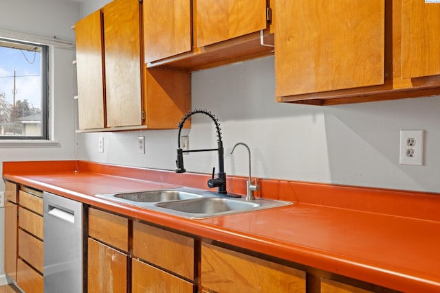 kitchen featuring brown cabinetry, light countertops, dishwasher, and a sink