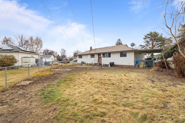 rear view of house with entry steps, a yard, and fence