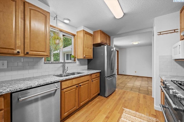 7009 W 8th Ave, Kennewick, WA 99336 - kitchen featuring stainless steel appliances, a sink, backsplash, light stone countertops, and a textured ceiling