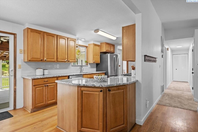 7009 W 8th Ave, Kennewick, WA 99336 - kitchen featuring appliances with stainless steel finishes, light stone counters, light wood-style floors, backsplash, and baseboards