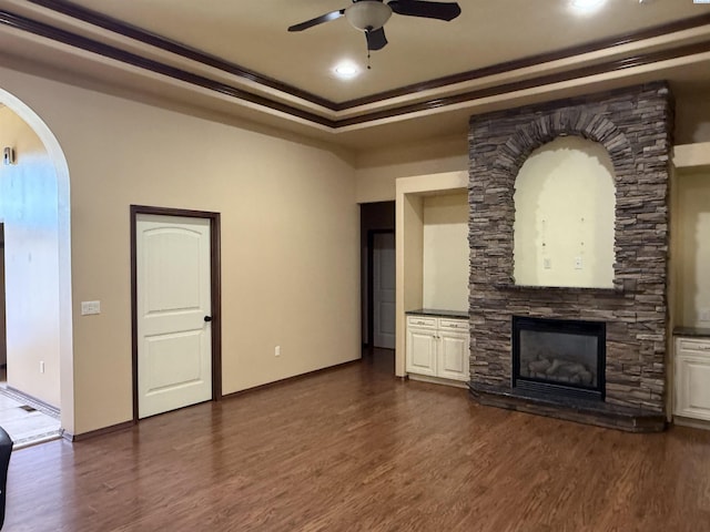 483 Aimee Dr, Richland, WA 99352 - unfurnished living room featuring ceiling fan, arched walkways, dark wood-style flooring, a stone fireplace, and ornamental molding