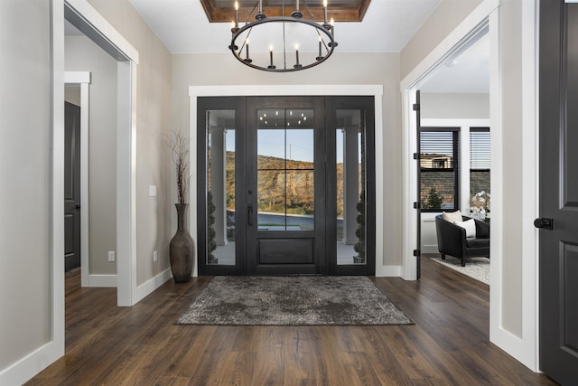 entrance foyer featuring dark hardwood / wood-style flooring, a chandelier, and a raised ceiling