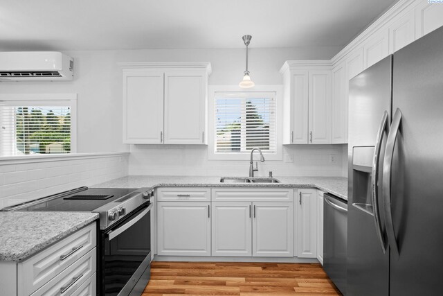205 W 8th St, Colfax, WA 99111 - kitchen with stainless steel appliances, a wall mounted air conditioner, white cabinetry, and light wood finished floors