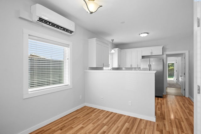 205 W 8th St, Colfax, WA 99111 - kitchen with stainless steel fridge with ice dispenser, an AC wall unit, white cabinetry, and light wood-type flooring