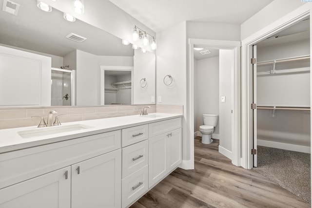 3054 S Quay St, Kennewick, WA 99338 - full bathroom with a walk in closet, double vanity, a shower stall, wood finished floors, and backsplash