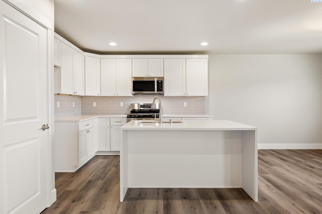3054 S Quay St, Kennewick, WA 99338 - kitchen featuring stainless steel appliances, light countertops, tasteful backsplash, a kitchen island with sink, and dark wood-style flooring