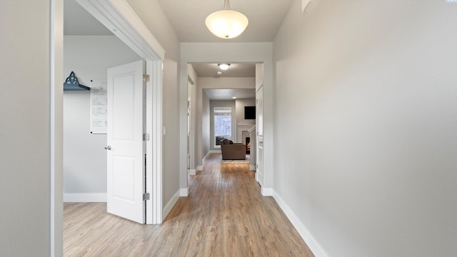 corridor with baseboards and light wood-style floors