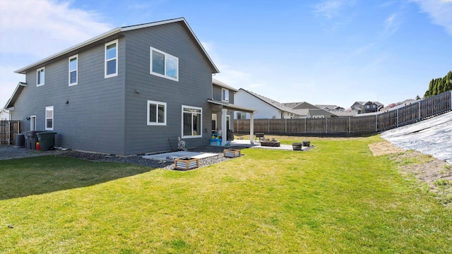 back of house featuring a patio, an outdoor fire pit, a lawn, and a fenced backyard