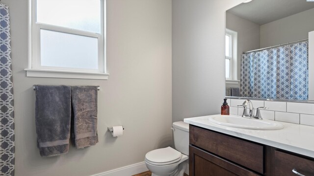 full bath featuring baseboards, toilet, backsplash, and vanity