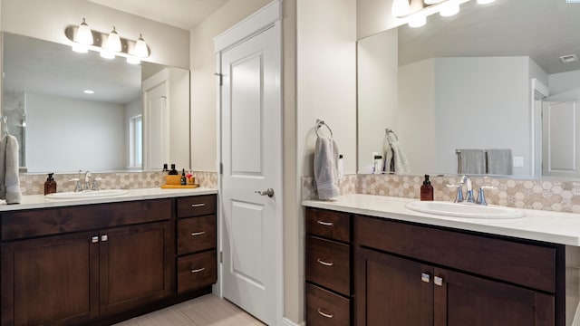 bathroom featuring visible vents, a sink, backsplash, and two vanities