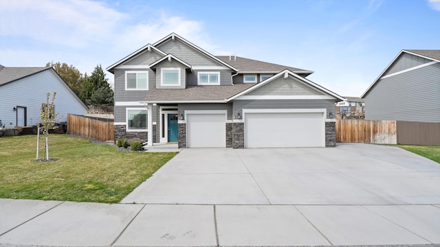 craftsman-style home featuring driveway, fence, stone siding, and a front yard