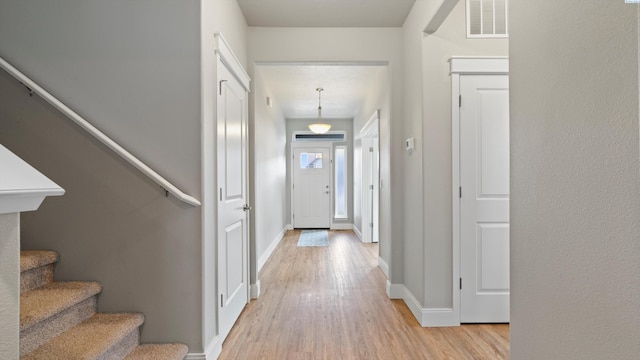 entryway with baseboards, visible vents, light wood-style floors, and stairway