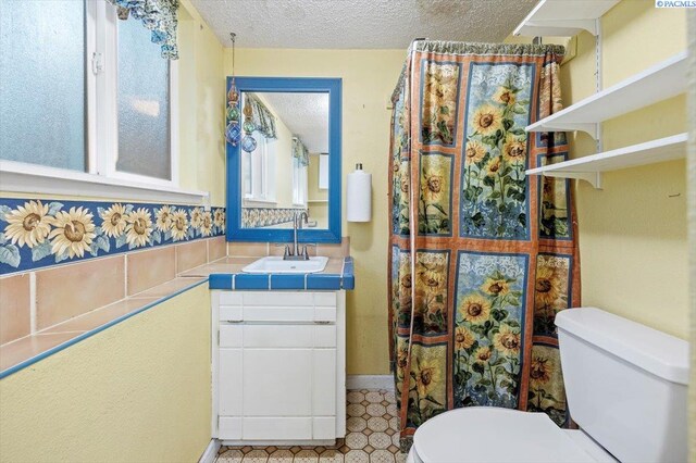 bathroom with vanity, toilet, and a textured ceiling