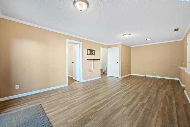 spare room featuring ornamental molding, a textured ceiling, and light wood-type flooring