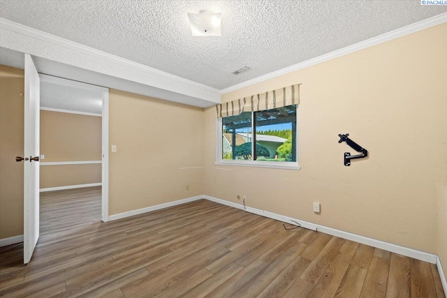 spare room featuring wood-type flooring, ornamental molding, and a textured ceiling