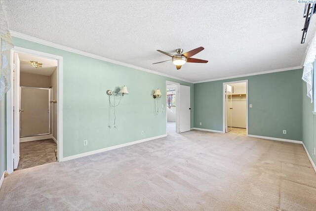 unfurnished bedroom with light colored carpet, ornamental molding, a spacious closet, and a textured ceiling