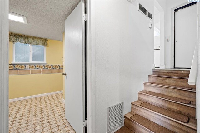 stairway featuring a textured ceiling