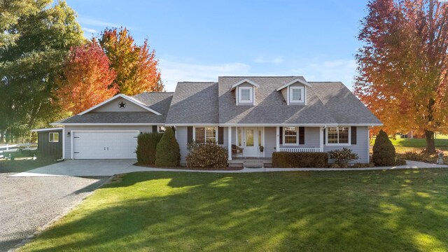 new england style home with a porch, a garage, and a front yard