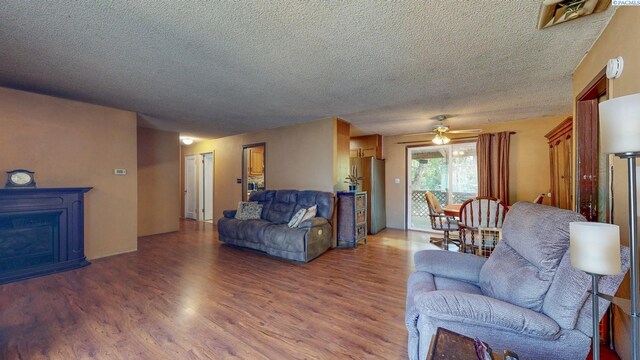 2816 S Cedar St, Kennewick, WA 99337 - living room featuring wood finished floors, a textured ceiling, ceiling fan, and a fireplace
