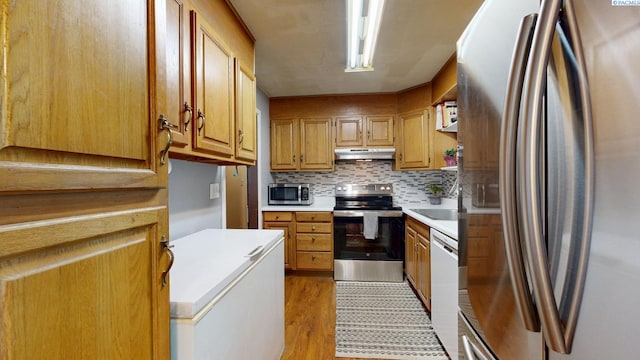 2816 S Cedar St, Kennewick, WA 99337 - kitchen with appliances with stainless steel finishes, under cabinet range hood, light countertops, light wood-style floors, and decorative backsplash
