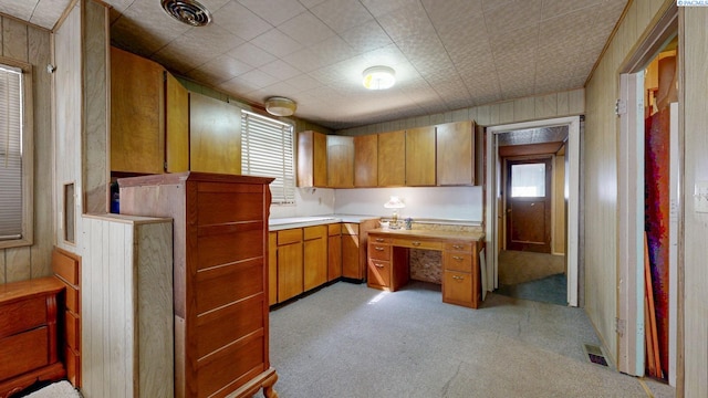 2816 S Cedar St, Kennewick, WA 99337 - kitchen with light colored carpet, light countertops, brown cabinetry, and wood walls