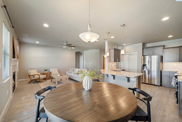 6223 Berea Ln, Pasco, WA 99301 - dining area featuring a lit fireplace, recessed lighting, light wood-type flooring, a ceiling fan, and arched walkways