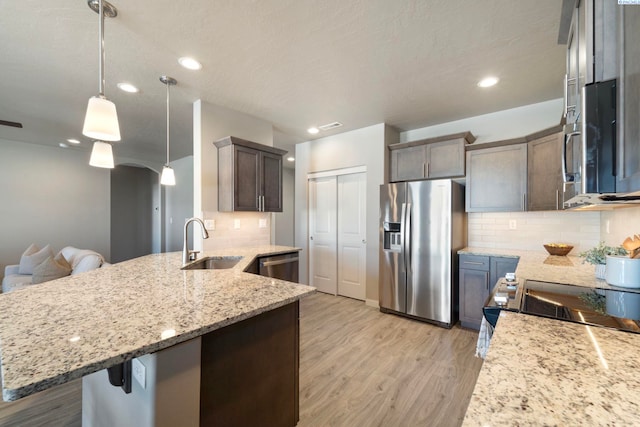 6223 Berea Ln, Pasco, WA 99301 - kitchen featuring stainless steel appliances, decorative backsplash, light stone counters, a peninsula, and light wood-type flooring