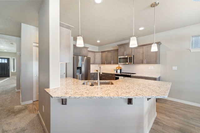 6223 Berea Ln, Pasco, WA 99301 - kitchen with appliances with stainless steel finishes, a breakfast bar, a peninsula, light stone countertops, and pendant lighting
