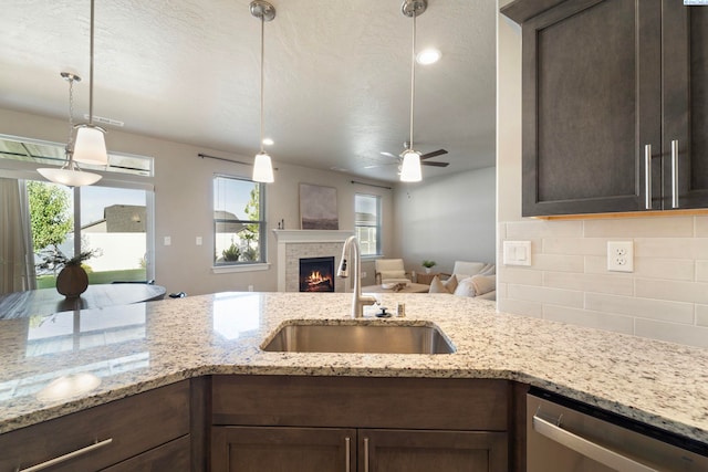 6223 Berea Ln, Pasco, WA 99301 - kitchen with dishwasher, backsplash, dark brown cabinetry, open floor plan, and a brick fireplace