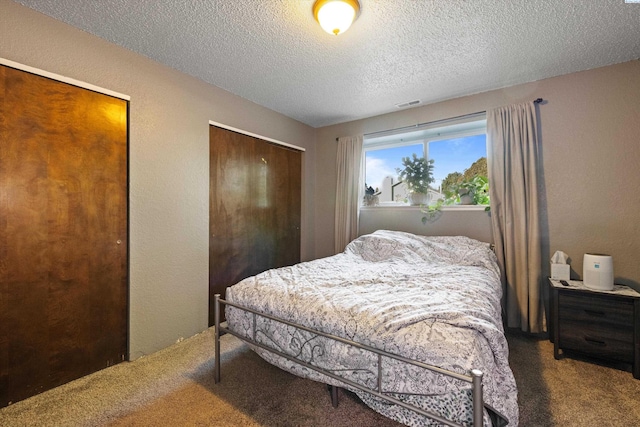 carpeted bedroom with multiple closets and a textured ceiling