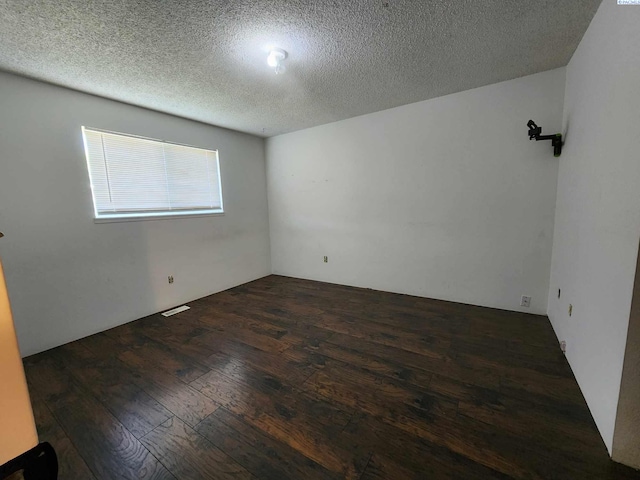 spare room featuring wood-type flooring, a textured ceiling, and visible vents
