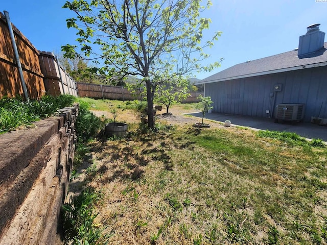 view of yard with a fenced backyard and central AC
