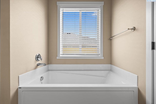 bathroom with a textured wall, a garden tub, and a wealth of natural light
