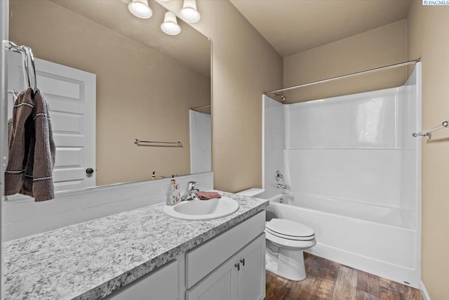 bathroom with toilet, shower / bath combination, wood finished floors, and vanity