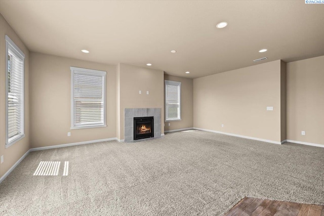 unfurnished living room with recessed lighting, carpet flooring, baseboards, and plenty of natural light