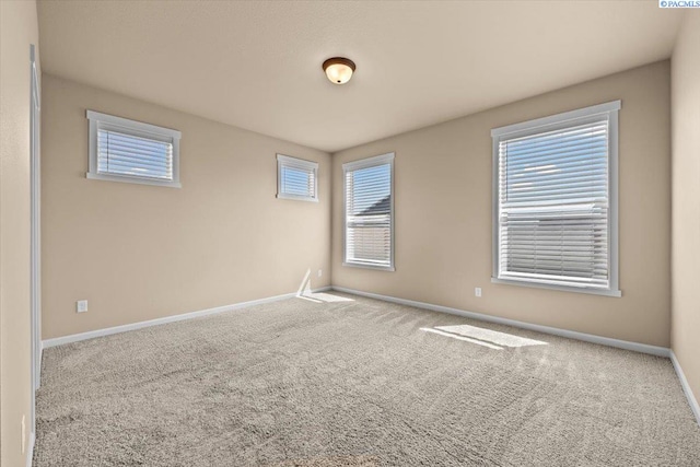carpeted spare room featuring baseboards