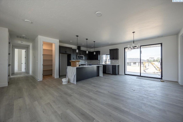 4218 W 19th Ave, Kennewick, WA 99337 - kitchen with stainless steel microwave, light wood-style floors, a center island, a chandelier, and hanging light fixtures