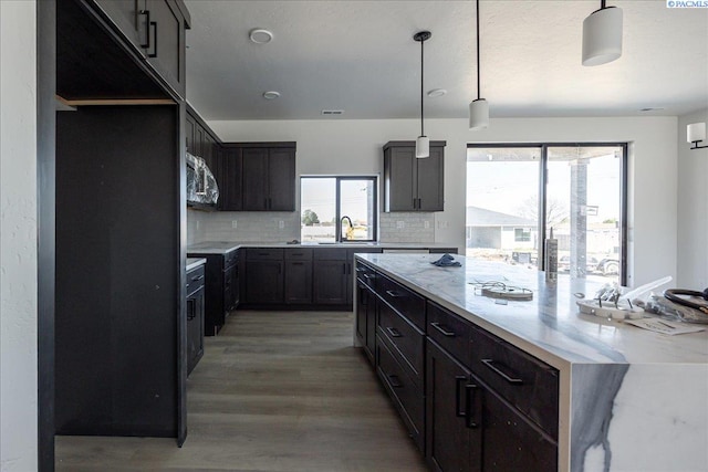 4218 W 19th Ave, Kennewick, WA 99337 - kitchen with a large island, stainless steel microwave, tasteful backsplash, light wood-style floors, and light stone counters