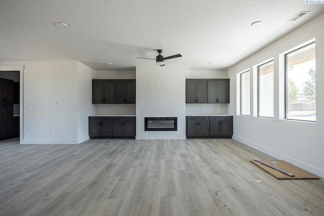 4218 W 19th Ave, Kennewick, WA 99337 - unfurnished living room featuring ceiling fan, light wood-style floors, a fireplace, and a textured ceiling